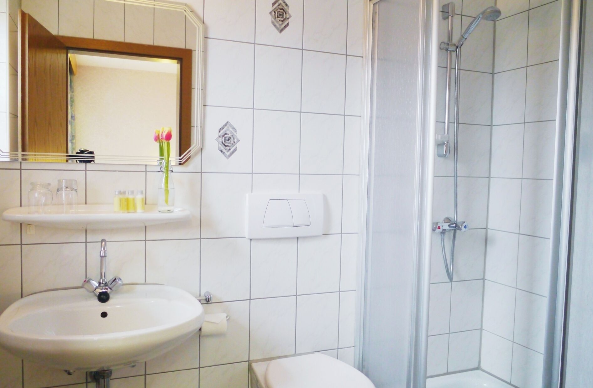 A bathroom with a sink, mirror, and shower.