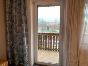 A room with a sliding glass door leading to a balcony with a wooden railing. - Landgasthof Zum Hirschen (Kemnath)