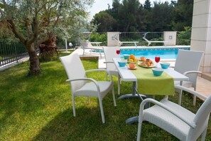 An outdoor dining area with a pool in the background. - Apartments Lumare with private pool (Pula)