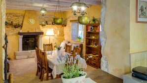 A rustic dining area with a stone wall, wooden ceiling, and hanging brass chandeliers. - Especially charm stone house with a pool (Marcana)