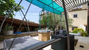 A patio area with a swing chair, outdoor furniture, and a water feature. - Especially charm stone house with a pool (Marcana)
