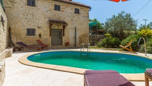 A stone building with a swimming pool, lounge chairs, and an umbrella. - Especially charm stone house with a pool (Marcana)