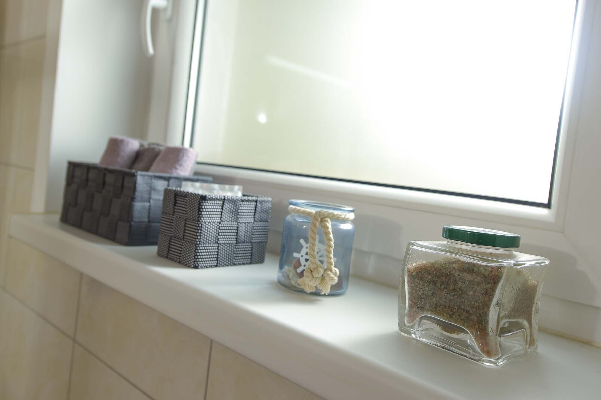 A window sill with storage boxes and jars.