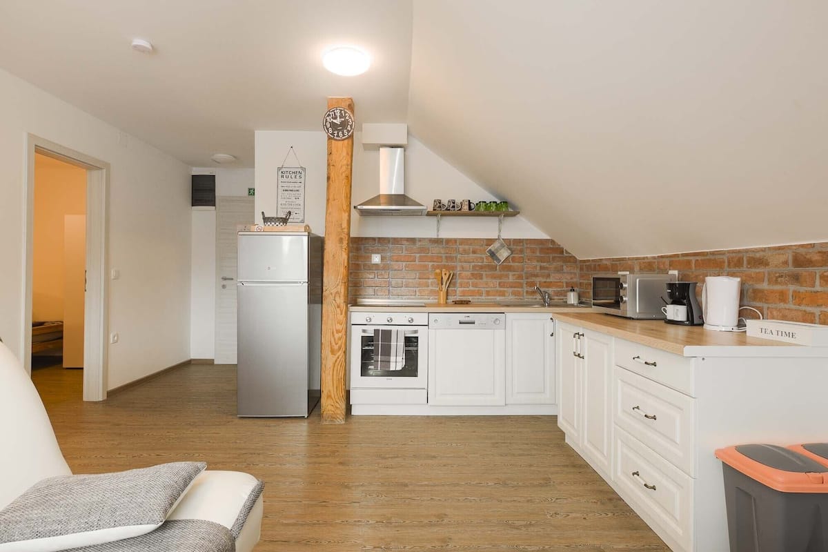 A compact kitchen with white cabinets, a refrigerator, a stove, and a microwave.