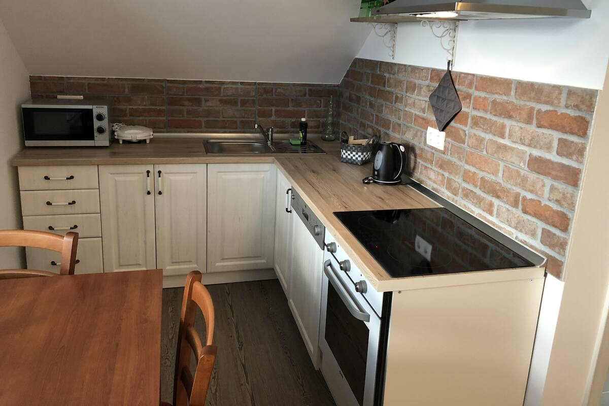 A compact kitchen with a microwave, kettle, and stove.
