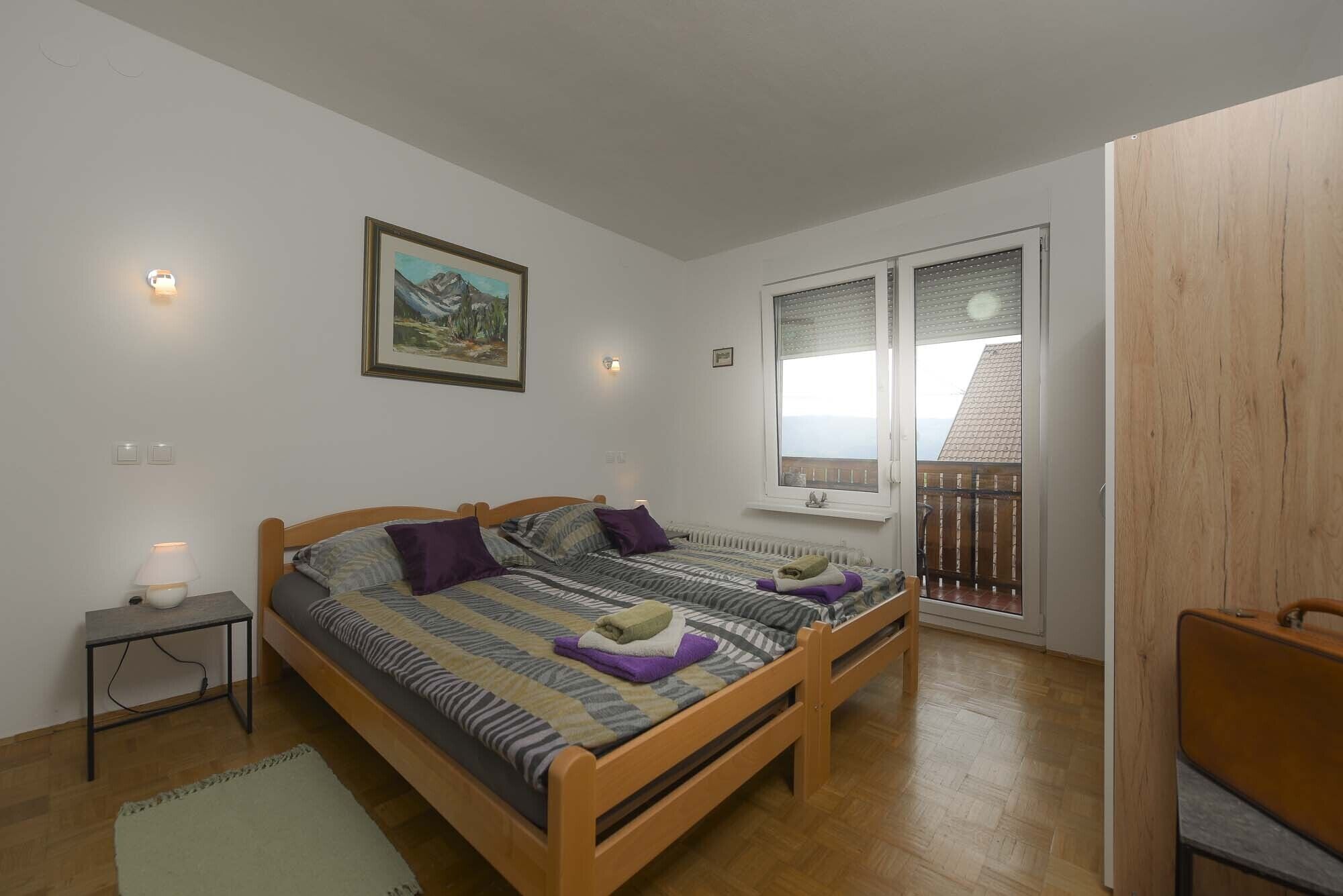 Une chambre avec deux lits en bois, une fenêtre donnant sur un paysage agréable et un radiateur.