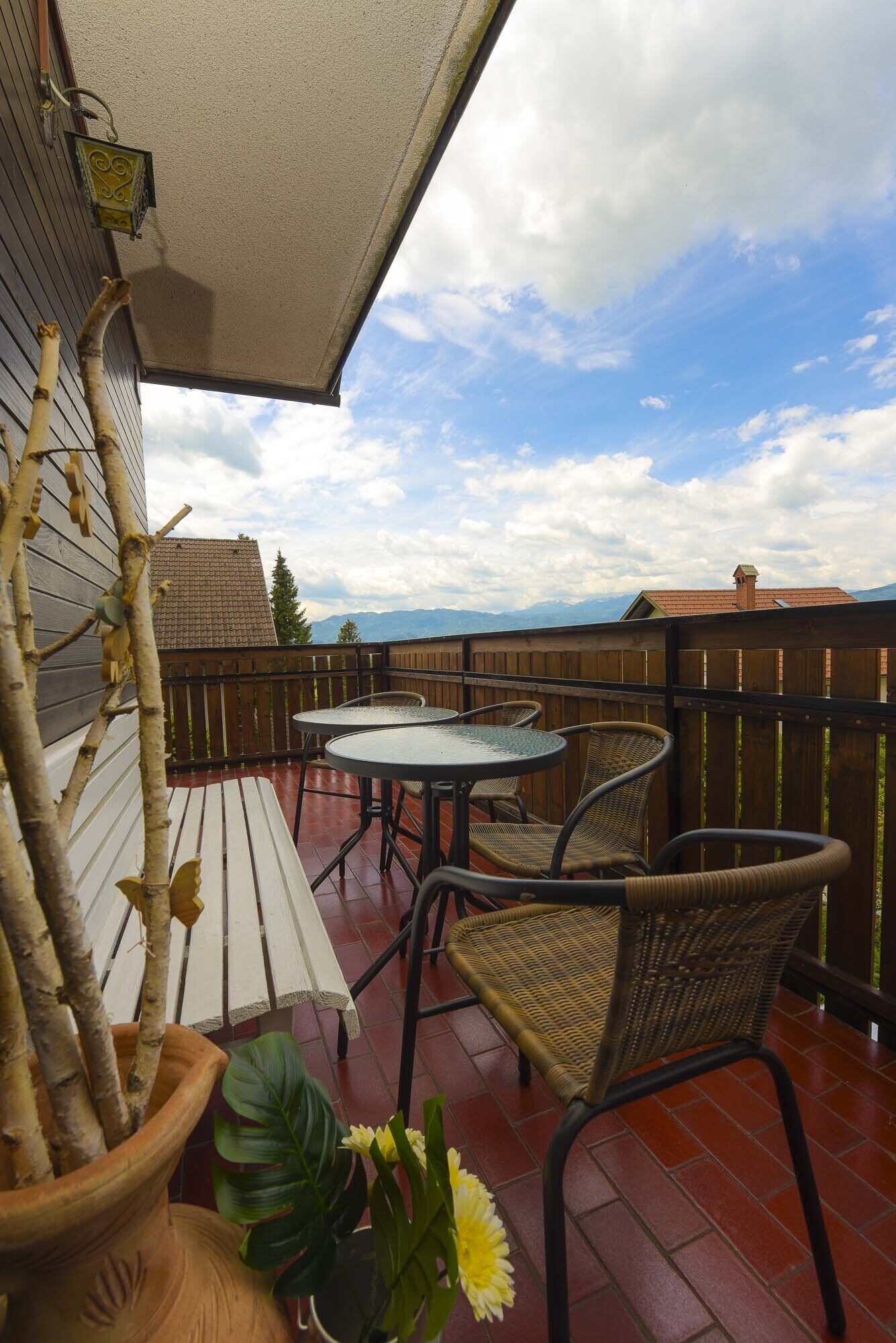 A patio with a table and chairs, a potted plant, and a view of the sky and mountains.