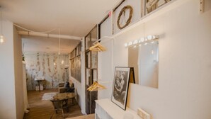 Une pièce comprenant un coin coiffeuse, un miroir avec éclairage, un tableau encadré et un porte-manteau.