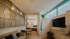 Une cuisine moderne dotée d’un grand téléviseur, d’un plancher en bois et d’un coin repas avec une table et des chaises.