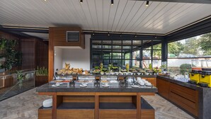 A modern kitchen with a central island, wooden cabinetry, and a large window providing a view of the outdoors. - Vital Hotel Fulya (Istanbul)