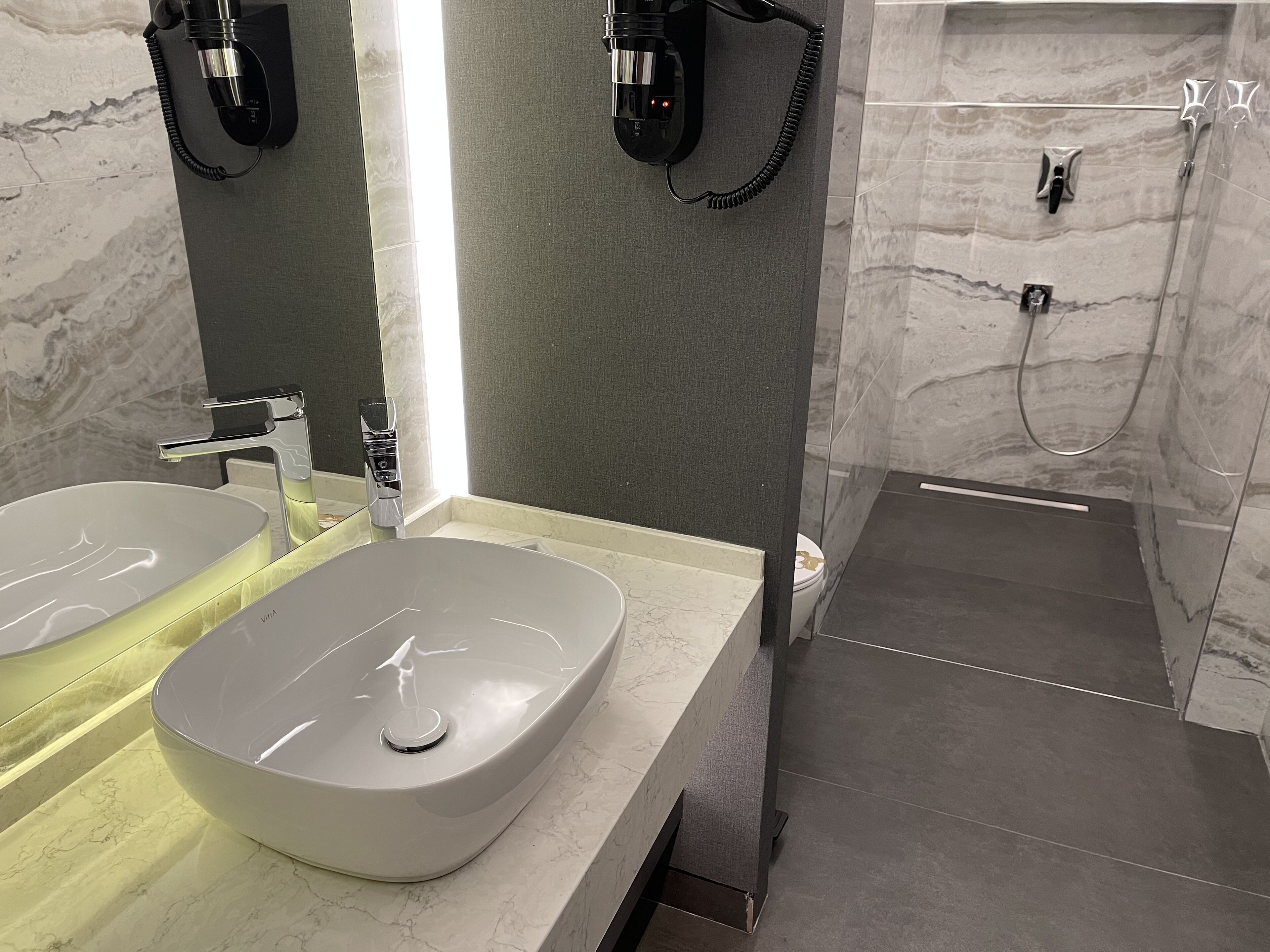 Ein modernes Badezimmer mit zwei Waschbecken, einem Spiegel und einer Duschkabine.
