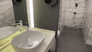 Ein modernes Badezimmer mit zwei Waschbecken, einem Spiegel und einer Duschkabine.