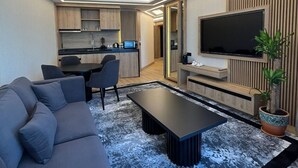 A modern living room with a grey sofa, a coffee table, and a TV mounted on the wall. - Vital Hotel Fulya (Istanbul)
