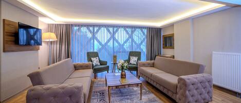 A modern living room with two sofas, a coffee table, and a TV mounted on the wall.