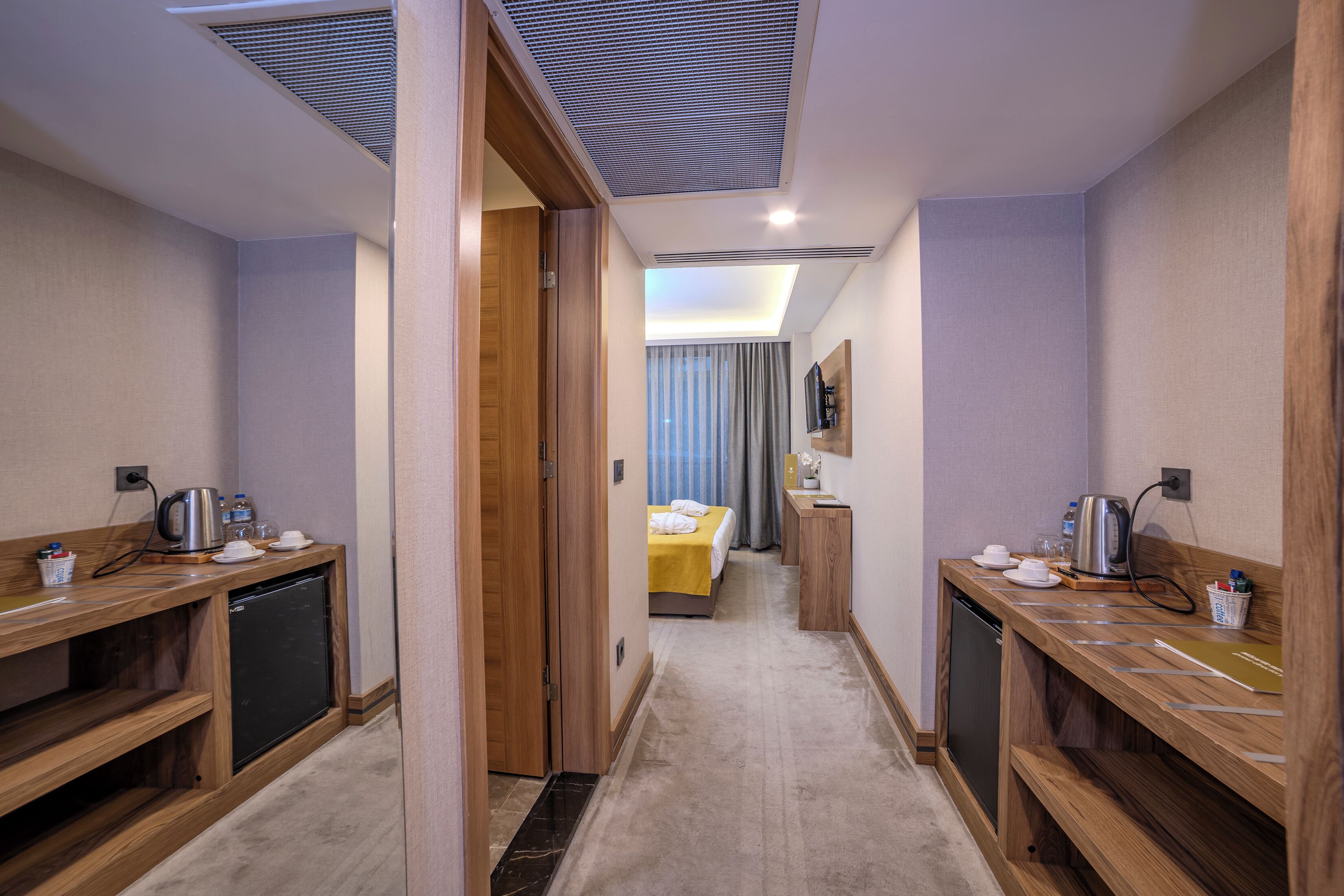 Habitación de hotel con cama, mesitas de noche, escritorio y kitchenette.