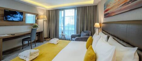 A hotel room with a large bed, a desk, a TV, and a painting on the wall.