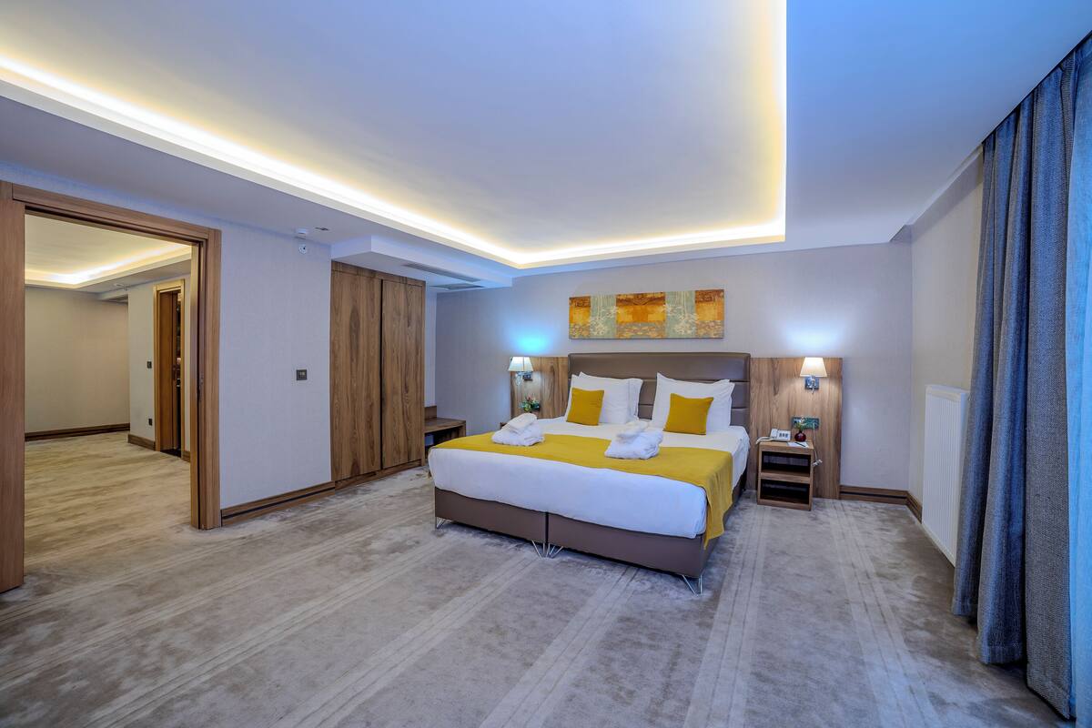 A hotel room with a large bed, bedside tables, a mirror, and a ceiling light.