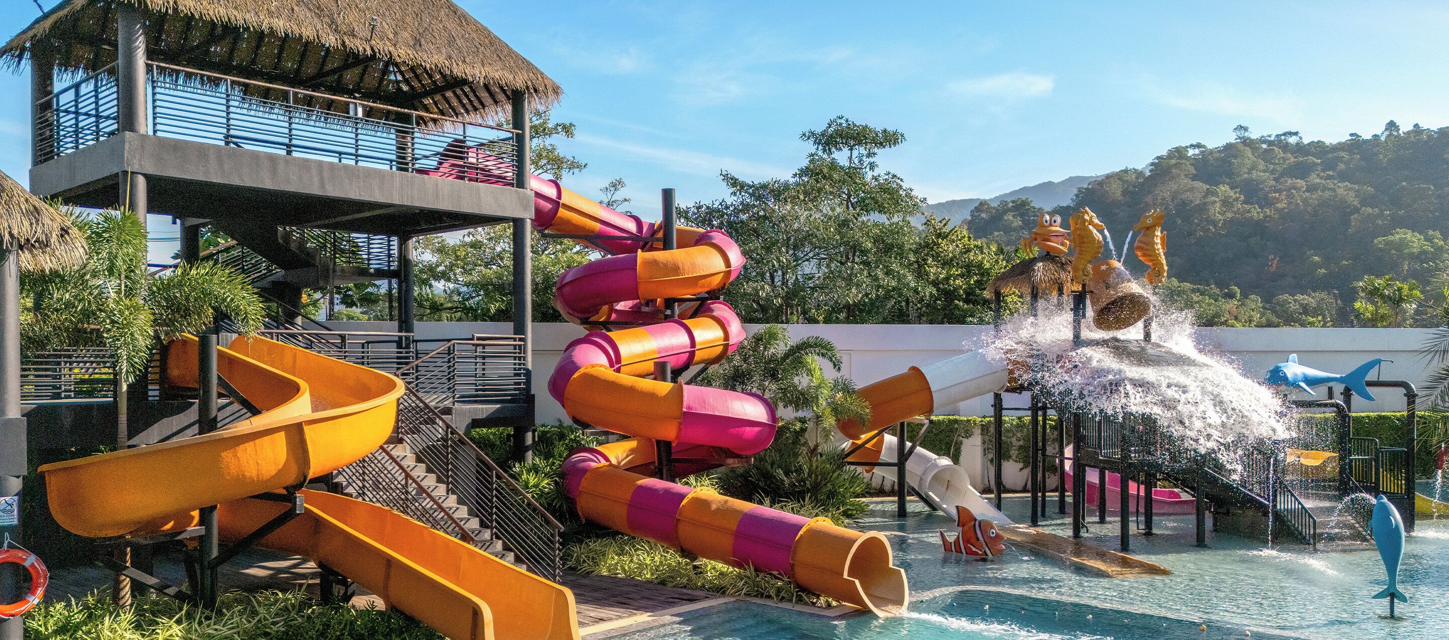 Un parque acuático con varias toboganes, una piscina y una estructura de techo de paja.