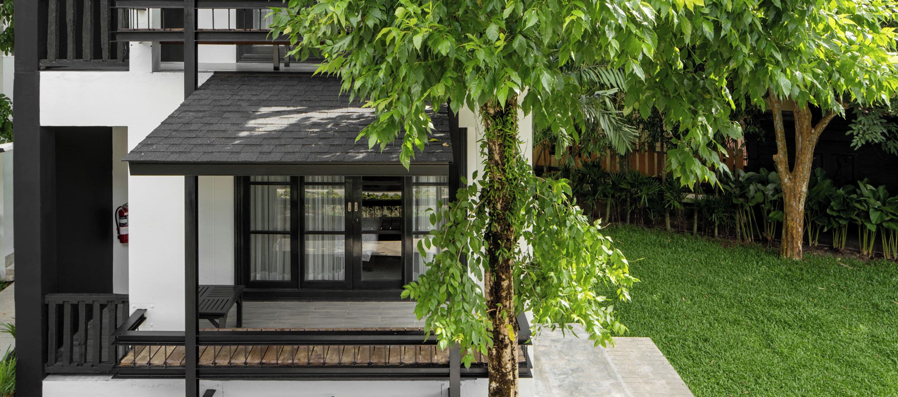A modern house with a covered porch, a fire extinguisher, and a well-maintained lawn.
