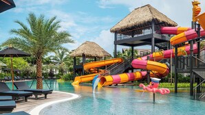 A pool area with lounge chairs, a water slide, and thatched-roof structures. - The Splash Koh Chang (Ko Chang)