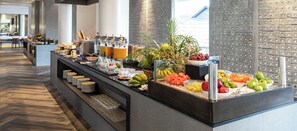 A buffet with various fruits and beverages, a seating area with chairs, and a modern interior design. - The Splash Koh Chang (Ko Chang)