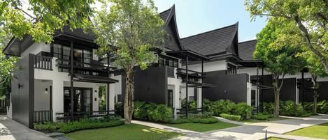 A modern building with a black and white facade, multiple balconies, and a well-maintained garden.
