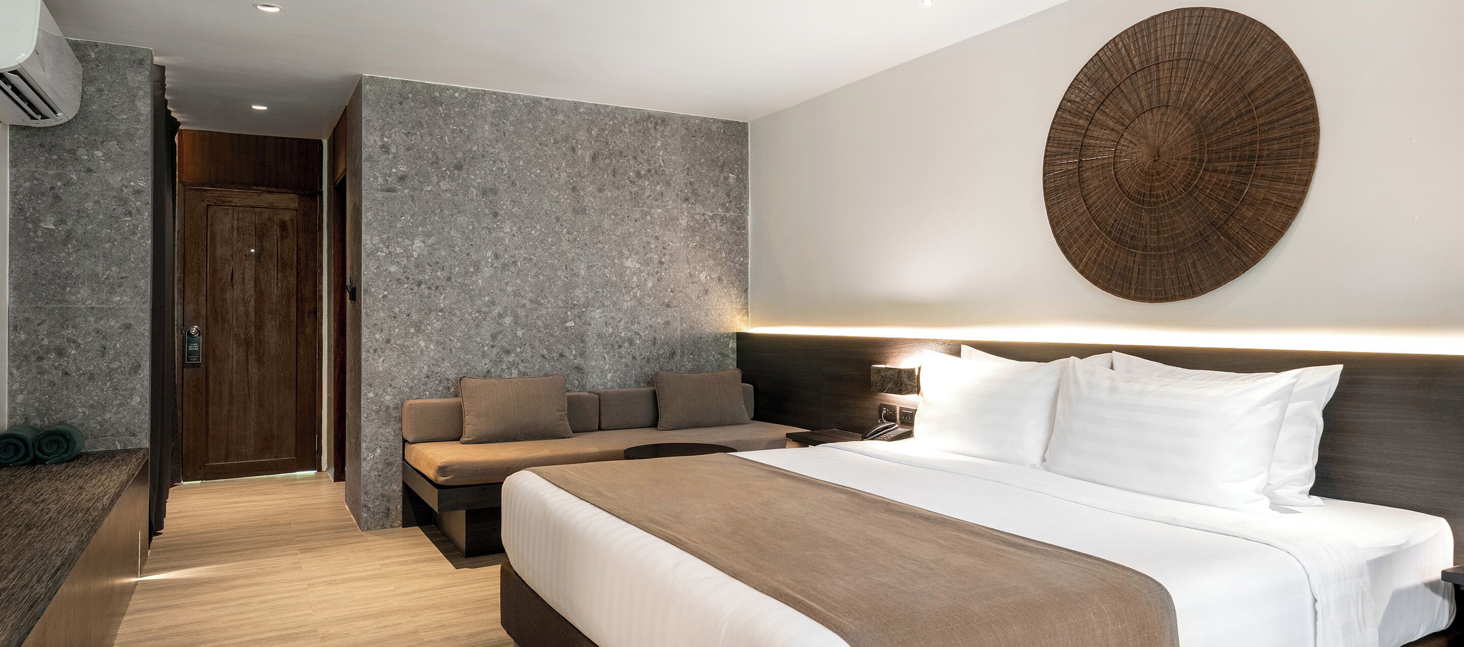Een moderne hotelkamer met een groot bed, een zithoek en een uniek kunstwerk aan de muur.