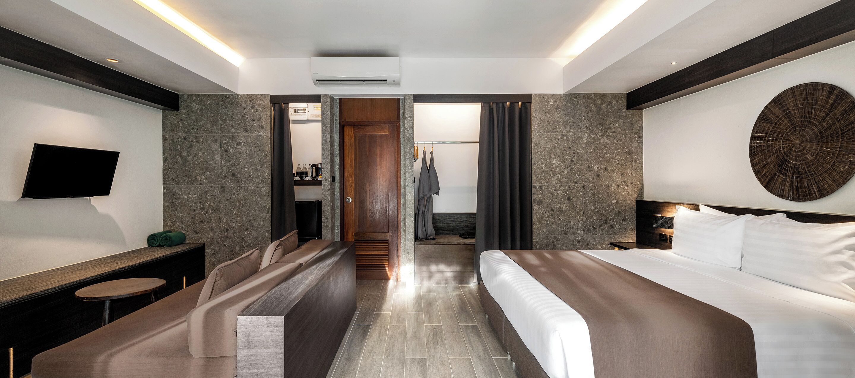 Une chambre d’hôtel moderne équipée d’un lit, d’un bureau, d’une télévision et d’un espace douche.