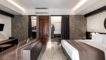 Une chambre d’hôtel moderne équipée d’un lit, d’un bureau, d’une télévision et d’un espace douche.