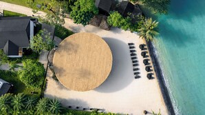 An aerial view of a beach with a large sandy area, a row of sun loungers, and a palm tree. - The Splash Koh Chang (Ko Chang)