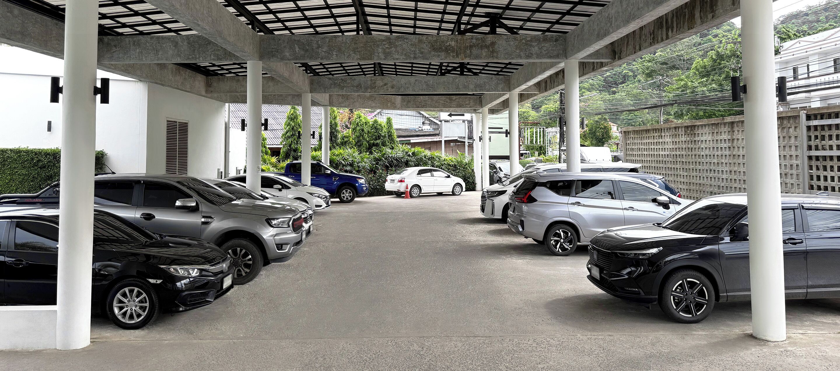 Un área de estacionamiento techada con varios coches aparcados bajo una estructura.