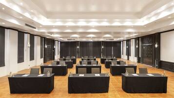 A conference room with multiple tables, chairs, and a tiled floor.