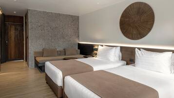 A hotel room with two beds, a sofa, a round wall decoration, and a wooden headboard.