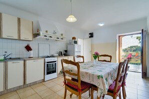 A compact kitchen with a dining area, featuring a stove, oven, and refrigerator.