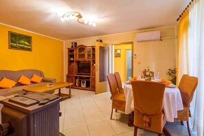 A living room with a sofa, coffee table, and TV stand. There is a dining area with a table and chairs. - Holiday house Emily with a pool (Vodnjan)