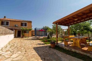 A courtyard with a stone floor, a wooden pergola, and a dining area with outdoor furniture. - Holiday house Emily with a pool (Vodnjan)
