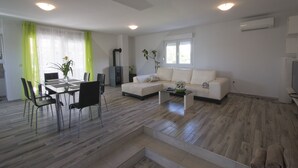 Una sala de estar moderna con comedor, que incluye un sofá, una mesa de centro y una mesa de comedor con sillas.
