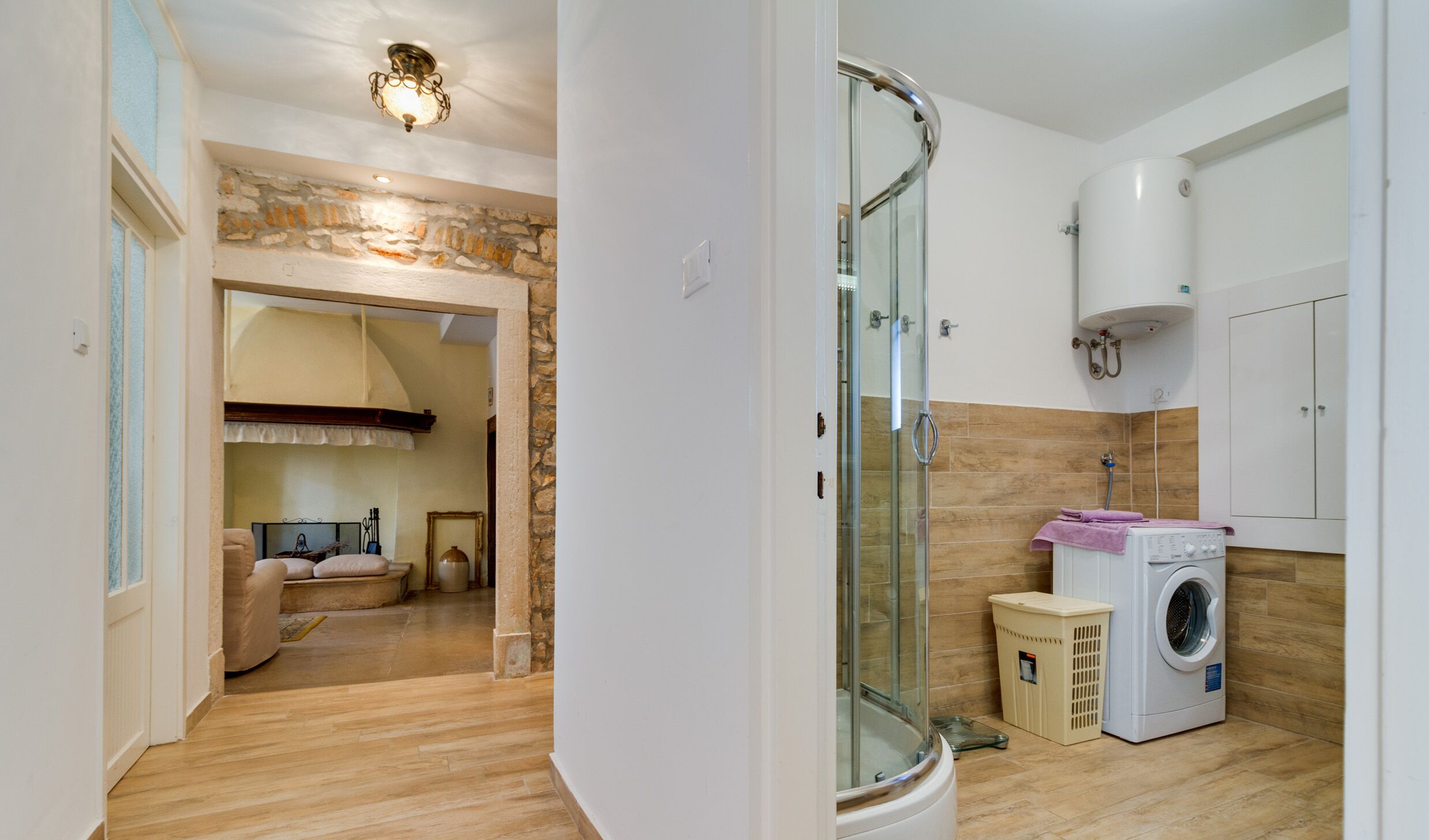 A modern bathroom with a glass shower enclosure, a washing machine, and a toilet.
