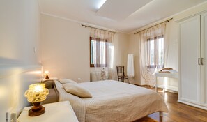 A bedroom with a bed, bedside table, lamp, chair, and wardrobe.
