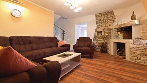 A living room with a brown leather sofa, a wooden coffee table, a stone fireplace, and a clock on the wall. - Lovely Villa Ana (Svetvincenat)