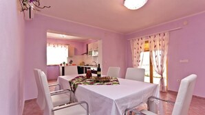 A dining area with a table set for four, white chairs, and a kitchen in the background. - Lovely Villa Ana (Svetvincenat)