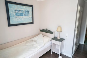 A single bed with a white headboard, a bedside table with a lamp, and a framed artwork on the wall. - Hotel Rogge Dünsen Waldfrieden (Dünsen)