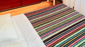 Une chambre moderne avec une grande armoire rouge, un petit banc blanc et un tapis rayé aux couleurs vives.