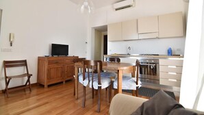 Un espace de vie compact comprenant un coin repas, une kitchenette et un téléviseur.