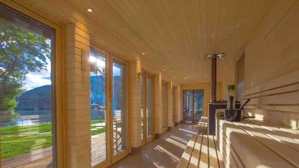 A modern hallway with large windows, wooden flooring, and a bench.