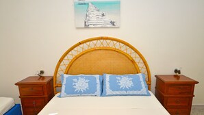 Ein Bett mit Holzkopfteil, zwei Nachttische und ein Gemälde eines Piers an der Wand.