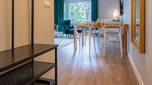 Een moderne woonkamer met een eetgedeelte, houten vloeren en een groot raam met gordijnen.