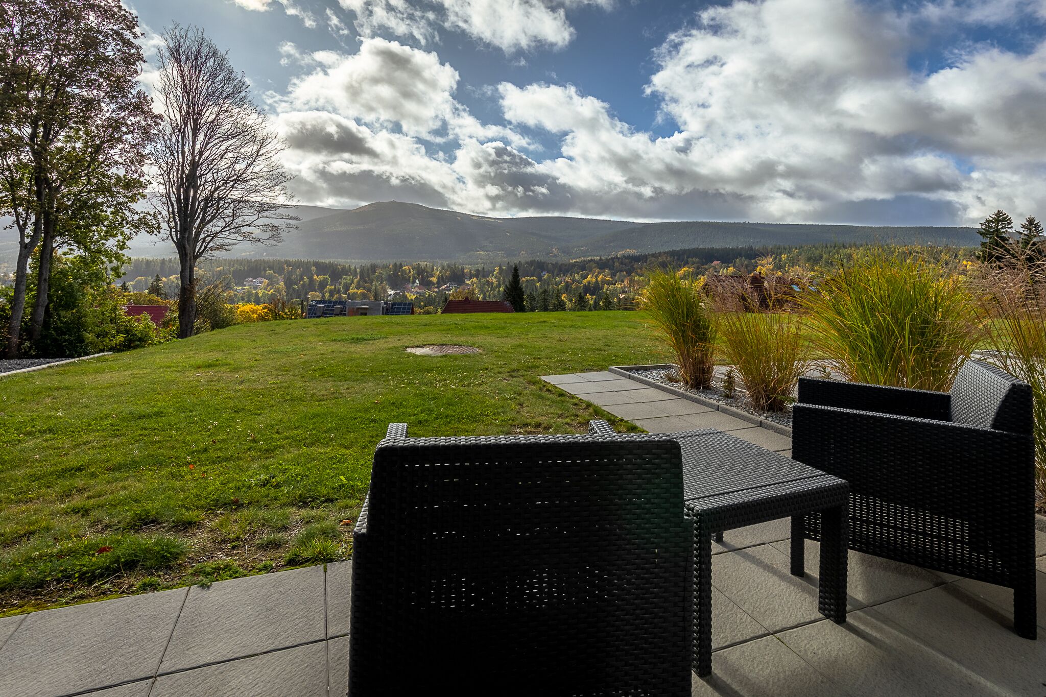 Eine Terrasse mit Gartenmöbeln und Blick auf eine gebirgige Landschaft.