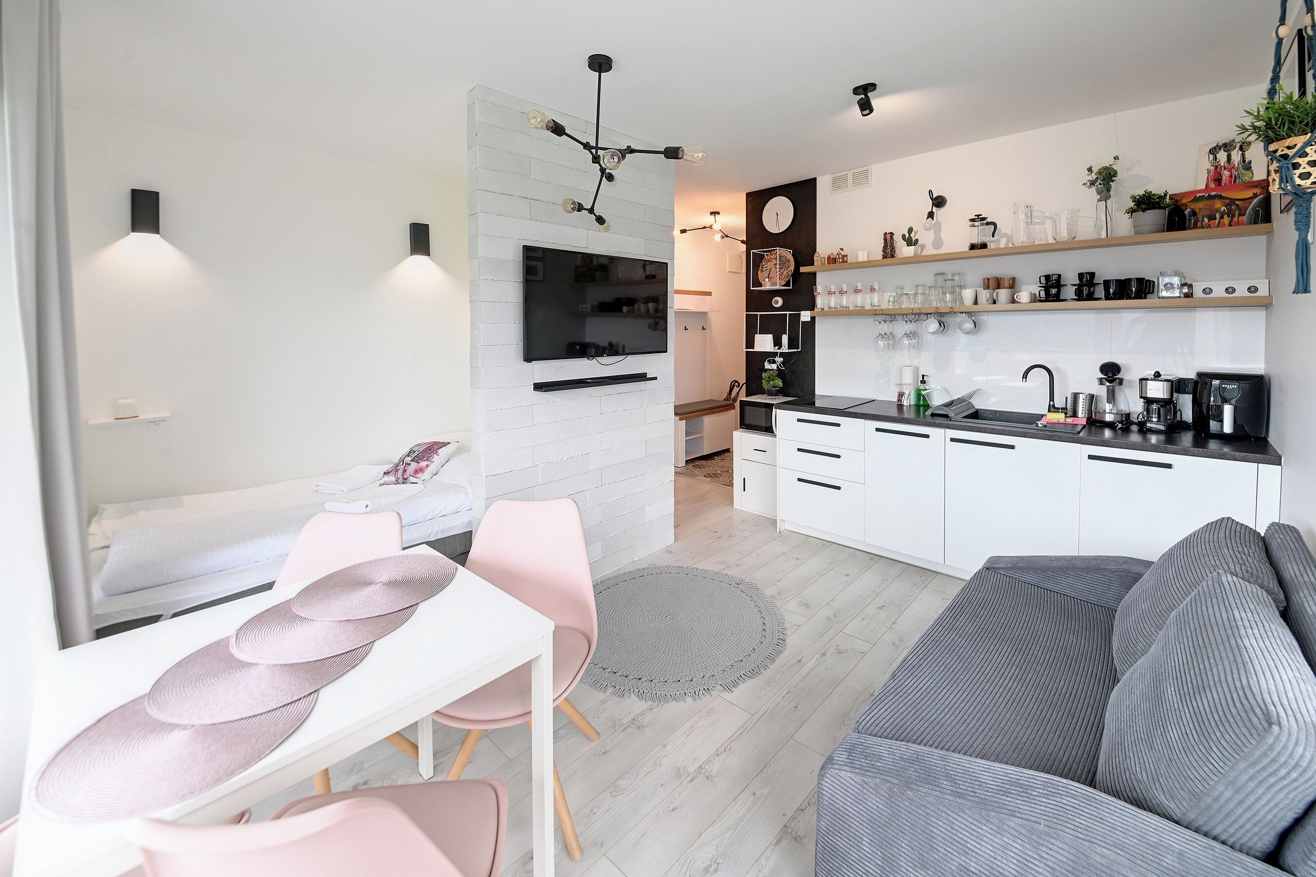 A modern kitchen with white cabinets, a built-in oven, and a coffee machine.