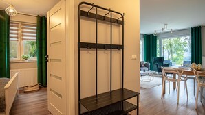 Een kamer met een bed, een zwarte metalen kast, een eettafel met stoelen en uitzicht op groen buiten.